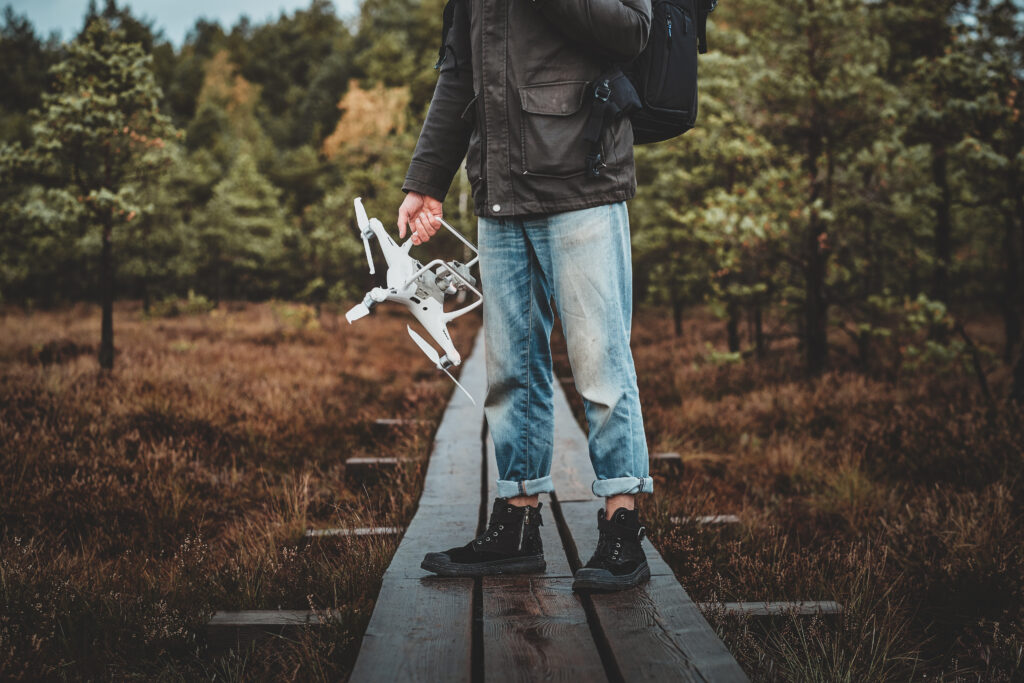 Young man is walking in forestal park with his drone
